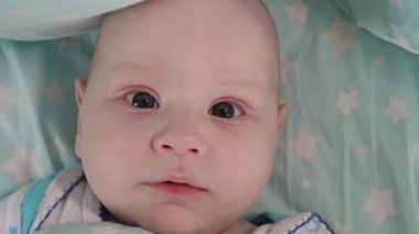 Küçük bir çocuk annesinin kollarında oturup kırmızı domateslerle oynuyor..