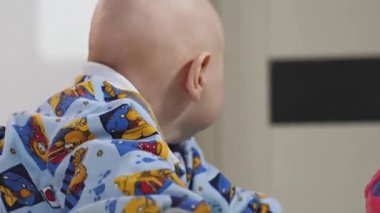 Küçük bir çocuk çıngıraklı yılanlar ve eğitici oyuncaklarla oynar. Bebek yerde tek başına yatıyor ve oynuyor. Bebek gelişiyor.