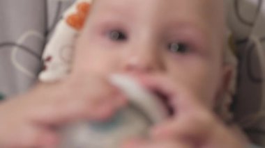 Bir bebek biberondan bebek maması yiyor. Bebeği yakın çekimde beslemek. Bebeğin kafası yakın çekimde.