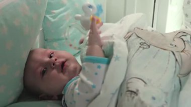Küçük bir çocuk beşiğinde uzanıyor ve kameraya bakıyor. Kafasına yakın plan..