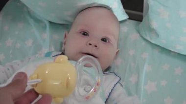 Küçük bir çocuk beşiğinde uzanıyor ve kameraya bakıyor. Kafasına yakın plan..