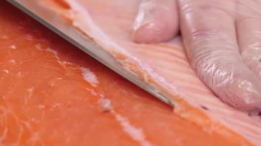 Erkeklerin elleri kırmızı balığı dikkatlice doğradı ve rulo yapmak için hazırladı. Yakın çekim. Çerçevede sadece eller var..