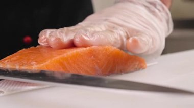 Erkeklerin elleri, rulo yapmak için kırmızı balığın üst tabakasını kesiyor. Çin yemeği için somon pişiriyor. Yakın plan.