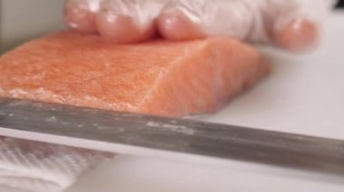 Erkeklerin elleri, rulo yapmak için kırmızı balığın üst tabakasını kesiyor. Çin yemeği için somon pişiriyor. Yakın plan.