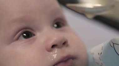 Küçük bir çocuk kaşıkla yemek yemek istemez. Bebeğim. Yüzü kapat. Anne bebeği besliyor.