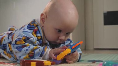 Bir bebek yerde eğitici oyuncaklarla oynuyor. Etrafta kimse yok. Güzel. Yakın çekim.