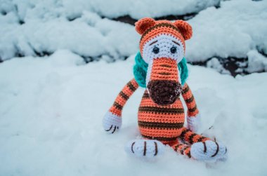 Örgü örmüş kaplan karda oturuyor. Yeni yıl fotoğrafı 2022.