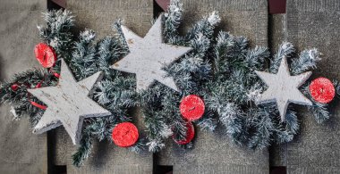 Ahşap beyaz yıldızlı yatay kompozisyon ve Noel ağacının arka planında kırmızı düğmeler. Noel fotoğrafı.
