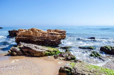 Kum sahili, kayalar ve deniz köpüğü. Doğal deniz manzarası fotoğrafı..