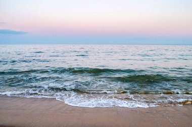 Yaz akşamları deniz kıyısı. Kumlu sahilde yumuşak deniz dalgasının görünümü.