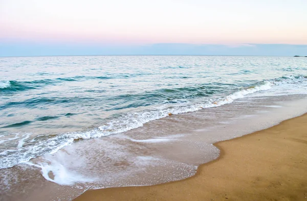 Yaz akşamları deniz kıyısı. Kumlu sahilde yumuşak deniz dalgasının görünümü.