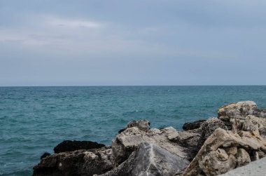 Turkuaz sığ su yüzeyi ve deniz tabanında taşlar. Yüzeysel saydam deniz suyu dipte kayalar var.