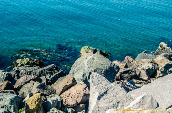 Turquoise shallow water surface and rocks stones on sea floor. Shallow transparent sea water rocks at the bottom