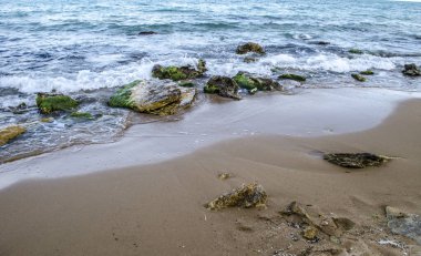 Turkuaz sığ su yüzeyi ve deniz tabanında taşlar. Yüzeysel saydam deniz suyu dipte kayalar var.