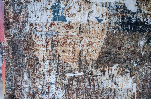 Torn ads old blue wall photo paper texture.Grunge peeling surface. Ragged old plaster background. Cracked paint on concrete wall. The wall texture with cracked plaster and whitewash for your design.