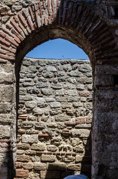 A stone arched window in the ruins of an ancient Mediterranean city. Architectural vintage detail photo.