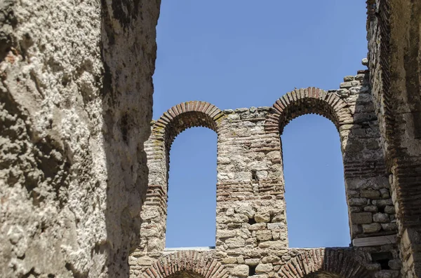 A stone arched window in the ruins of an ancient Mediterranean city. Architectural vintage detail photo.