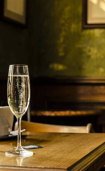 Sparkling wine in a glass with bubbles on the background of a vintage house. Alcoholic drink photo.