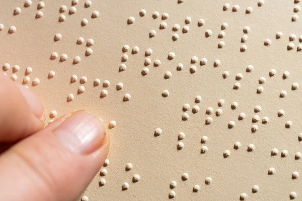 Kör alfabesiyle yazılmış bir sayfayı okuyan bir parmak. Körler için dokunsal okuma sistemi.