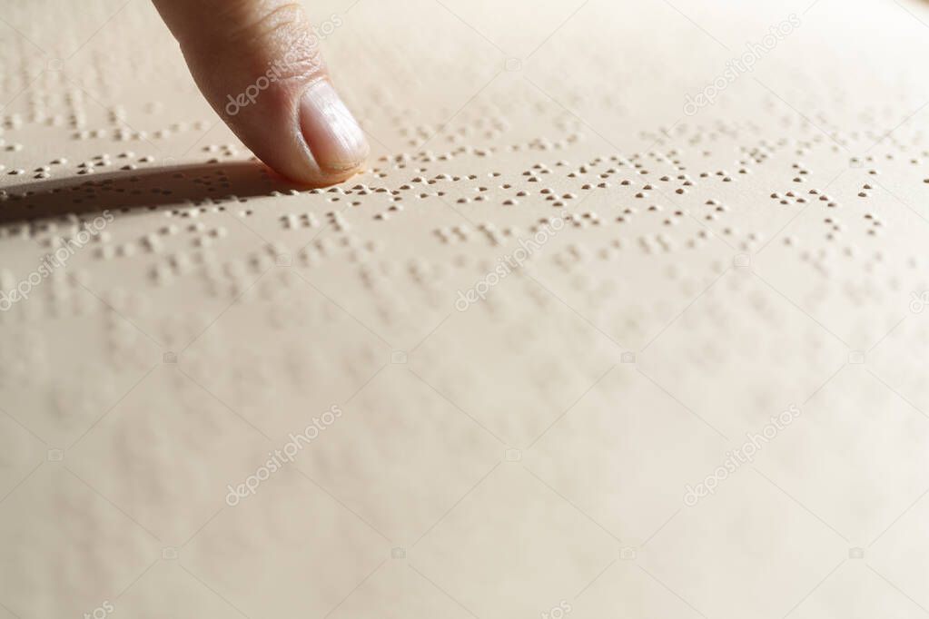 a finger following the reading of a page written in the Braille alphabet, the tactile reading system in relief for the blind