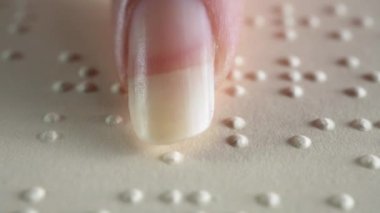 Bir kız Braille alfabesinde yazılmış bir kitabın sayfasını okurken.