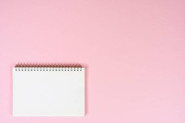 Pembe bir yüzeyde boş beyaz bir not defteri