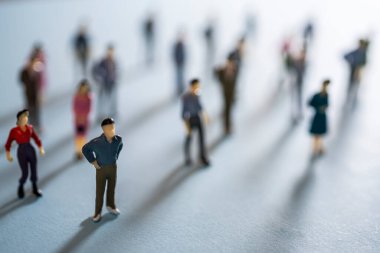 Renkli bir yüzeyde bir grup minyatür insan.