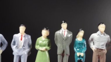 Siyah arka planda bir sıra minyatür insanın kaydırılması.