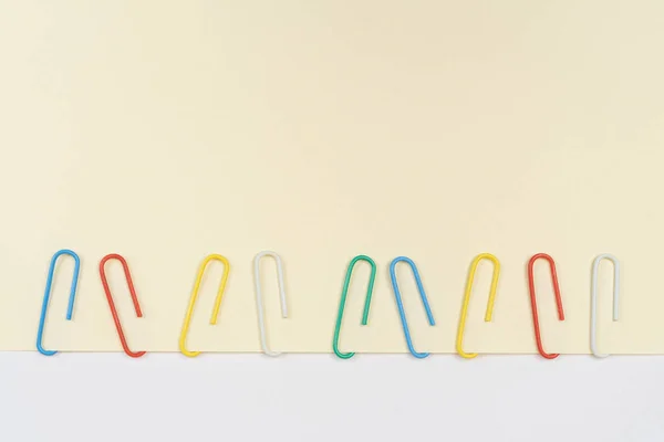 Een Rij Gekleurde Paperclips Een Blanco Vel Papier — Stockfoto