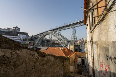 Porto, Portekiz. Mart 2022, şehir merkezinin eski evleri arasında arka planda Dom Louis I demir köprüsü olan nehre doğru giden tipik bir cadde.