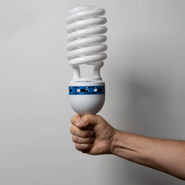 a huge low-energy electronic light bulb in his hand