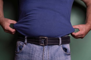 a man touching his hips to measure the layer of fat in his body.