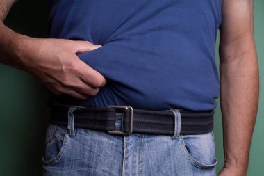 a man touching his belly to measure the layer of fat in his body.