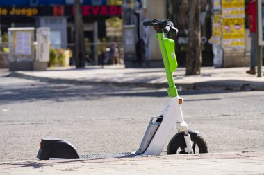 Şehir merkezinde caddenin kenarına park etmiş elektrikli bir scooter.