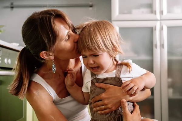 Genç anne ağlayan küçük kızını sakinleştirmeye çalışıyor. Çocuk yetiştirme kavramı.