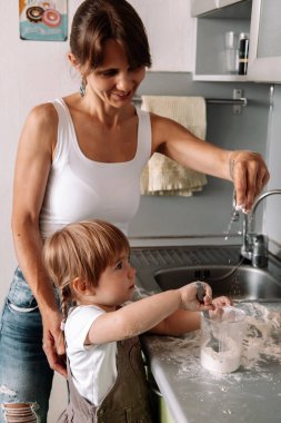 Anne ve küçük kızın gizli portresi mutfakta zencefilli kurabiye için hamur hazırlıyor. Mutlu aile, rahat daireler..