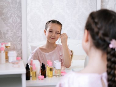 Yatak odasında makyaj yapan sevimli küçük bir bayan. Hafif ve havadar portre.