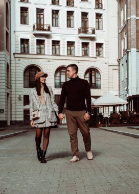 Moda bir çiftin samimi portresi. Kadın ve erkek, şehrin arka planında birbirlerini izliyorlar. Sonbahar randevusu. Aşk ve mutluluk.