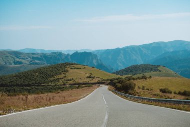 Güneşli bir yaz gününde dağlarda boş bir yol.