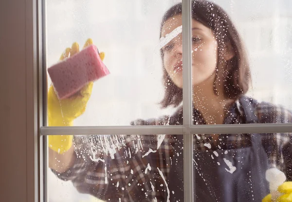 Mulher lava as janelas com um detergente. — Fotografia de Stock