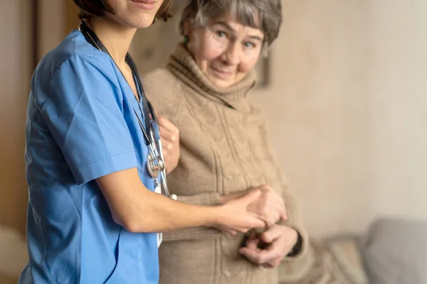 一位年轻的护士对一位老年妇女表现出关心和专业精神. — 图库照片