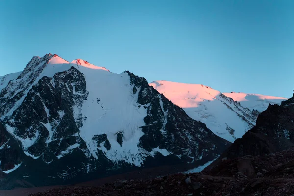 Hautes montagnes enneigées au coucher du soleil. — Photo