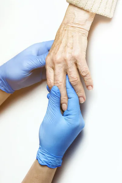 Doctors hands in a blue gloves holds the hands of an elderly woman, a patient. — Stock Photo, Image