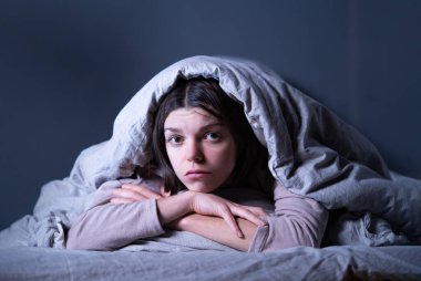 Battaniyeye sarılı bir kadın uykusuzluk ve stresten endişeleniyor..