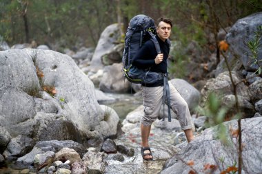 Genç bir adam, bir gezgin. Sırt çantası ve turistik ekipmanları var.