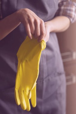 Sarı lastik eldivenli bir kadın ev işi yapar.