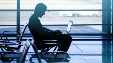 Adam havaalanında dizüstü bilgisayarla çalışıyor..