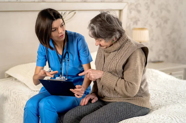 Young nurse is caring for an elderly 80 year-old woman at home. — Stock Photo, Image