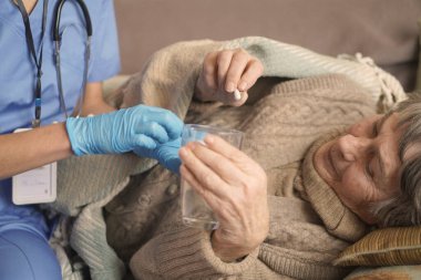 Genç bir hemşire evde 80 yaşında yaşlı bir kadınla ilgileniyor..