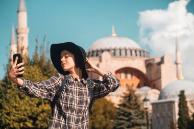 Şık şapkalı ve ekose gömlekli güzel bir kız poz veriyor.,